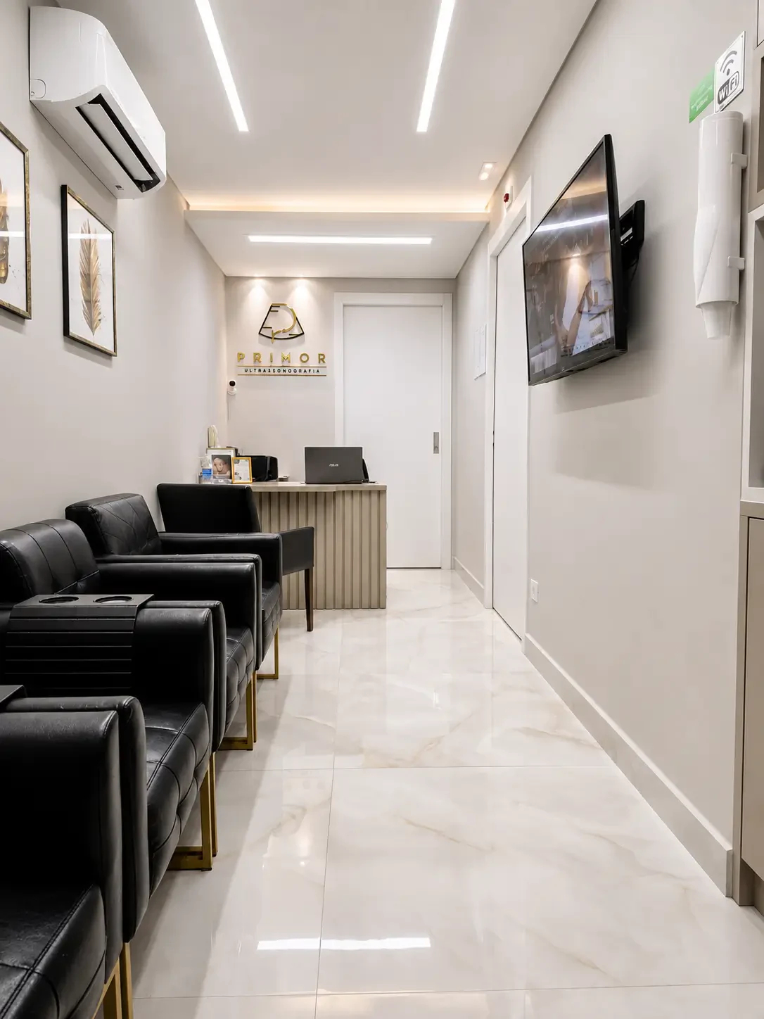 Recepção da Primor, com poltronas pretas, piso de mármore claro e luz indireta